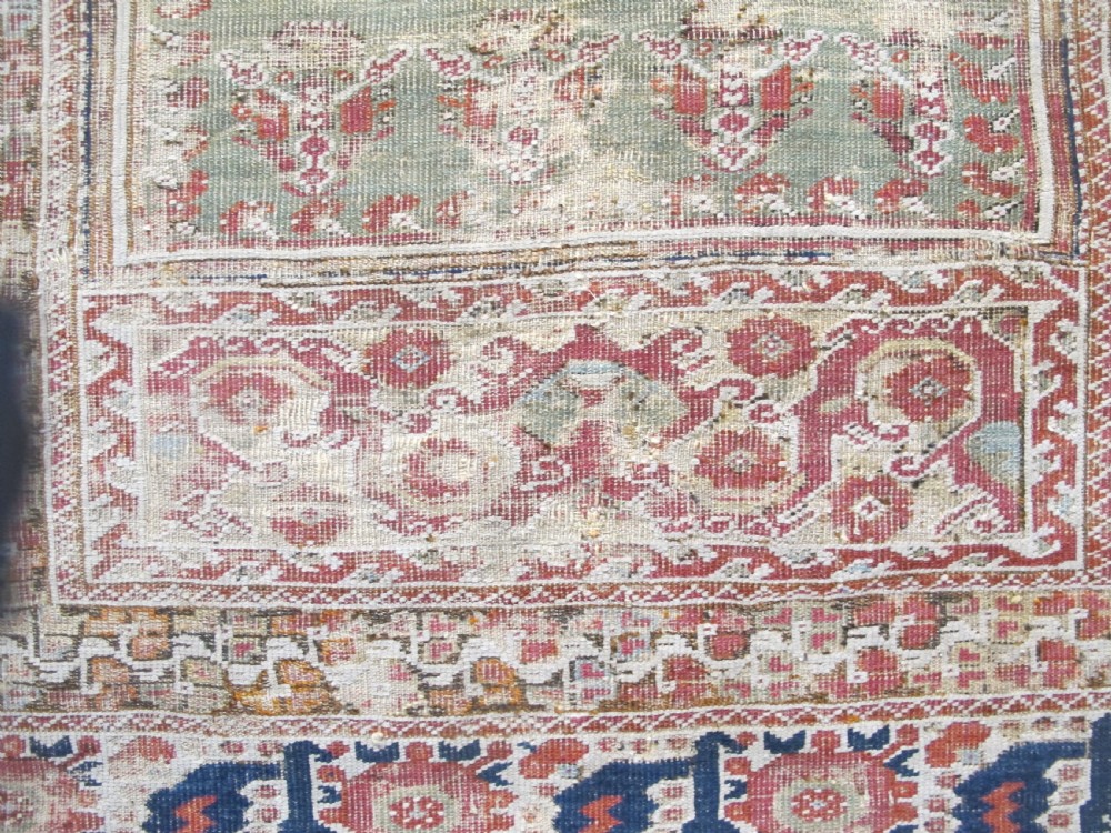 An 18th-century hand-knotted Ghiordes prayer rug featuring a central pale green mihrab niche framed by intricate floral borders in red, blue, and beige. View IV