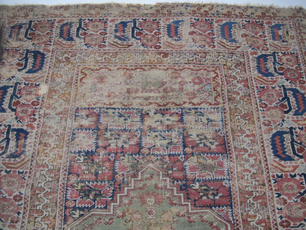 An 18th-century hand-knotted Ghiordes prayer rug featuring a central pale green mihrab niche framed by intricate floral borders in red, blue, and beige. View V
