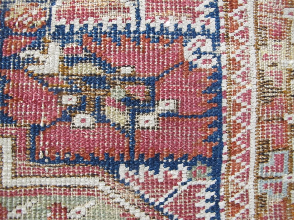 An 18th-century hand-knotted Ghiordes prayer rug featuring a central pale green mihrab niche framed by intricate floral borders in red, blue, and beige. View X