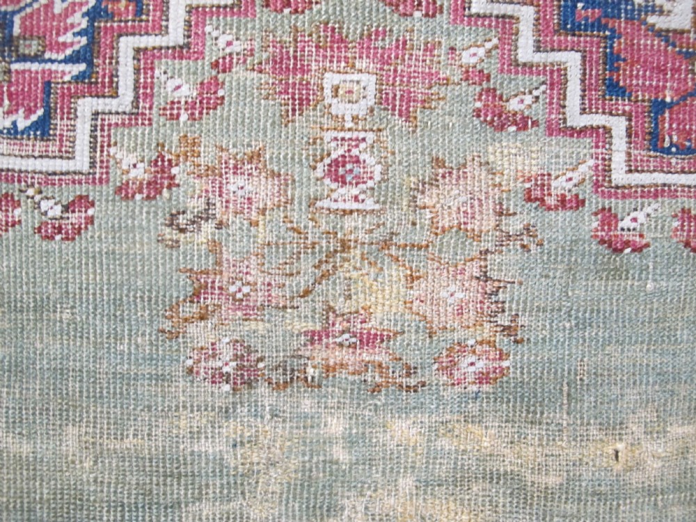 An 18th-century hand-knotted Ghiordes prayer rug featuring a central pale green mihrab niche framed by intricate floral borders in red, blue, and beige. View XII