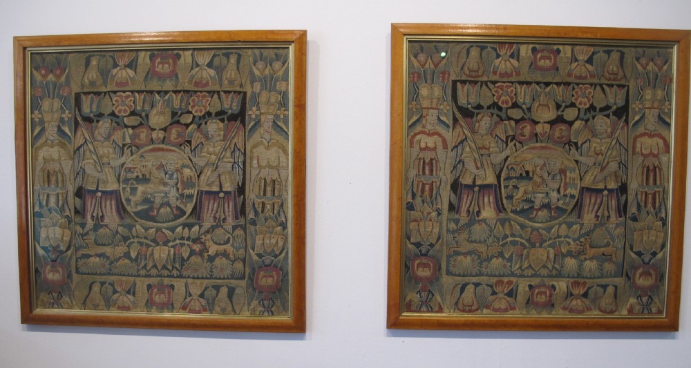 A pair of square 17th-century North German tapestry panels featuring allegorical figures and floral borders, presented in wooden frames.
