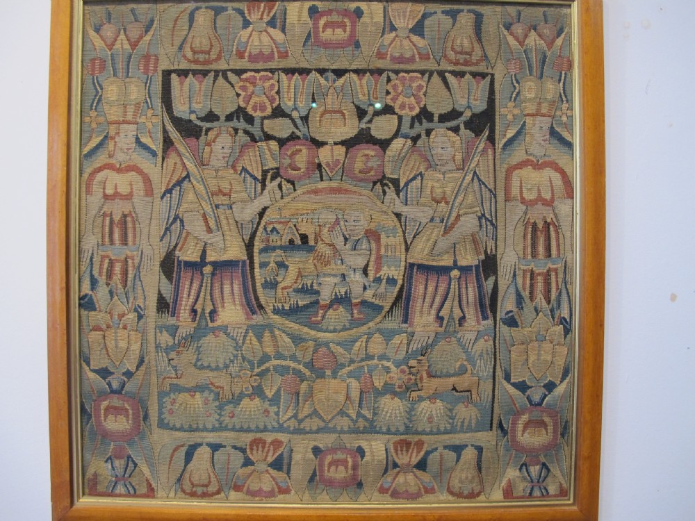 A pair of square 17th-century North German tapestry panels featuring allegorical figures and floral borders, presented in wooden frames. View III