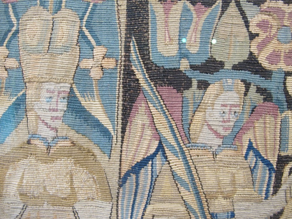 A pair of square 17th-century North German tapestry panels featuring allegorical figures and floral borders, presented in wooden frames. View X