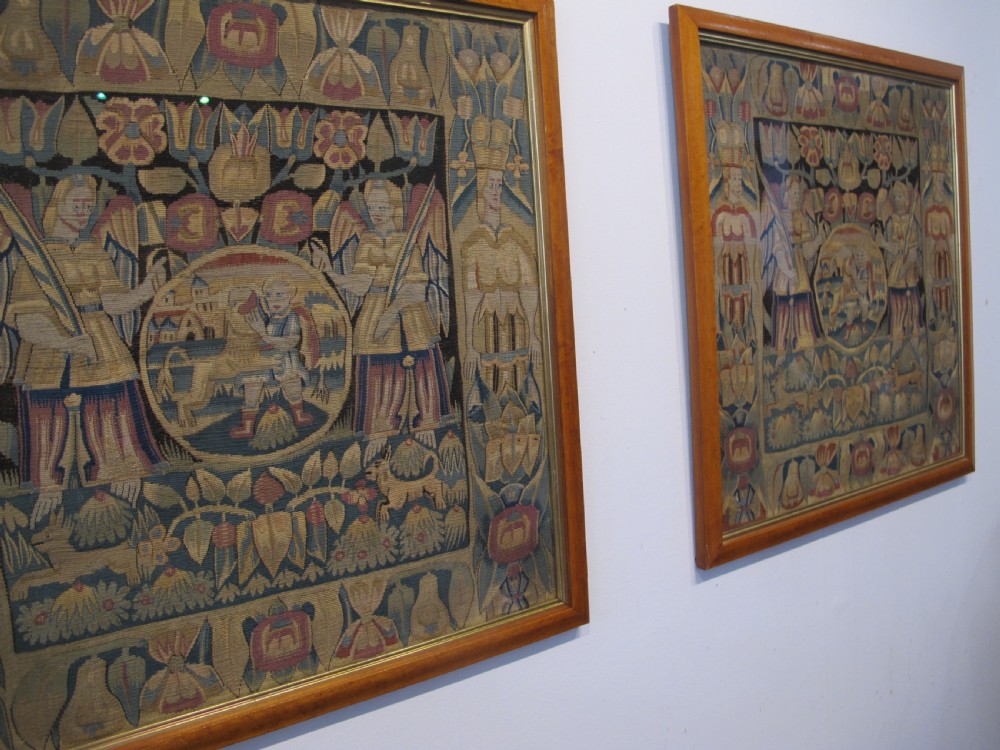 A pair of square 17th-century North German tapestry panels featuring allegorical figures and floral borders, presented in wooden frames. View XII