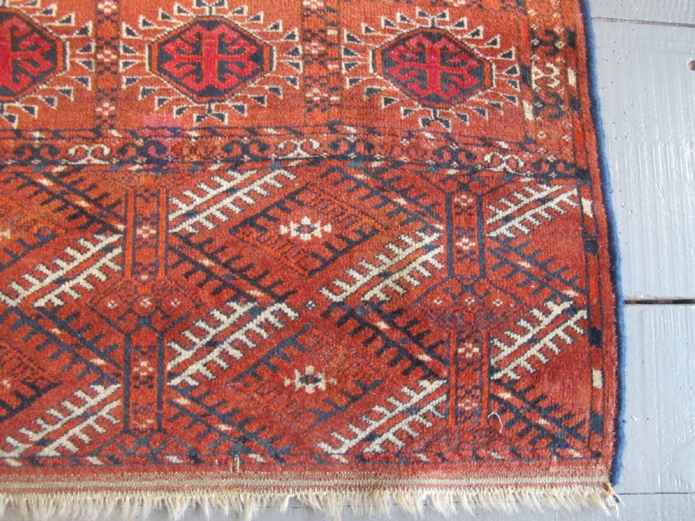 An antique hand-knotted Central Asian wool carpet featuring repeating rows of octagonal gol motifs on a terracotta red ground with detailed borders. View II