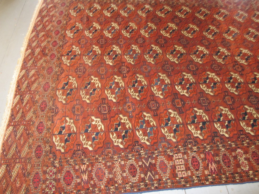 An antique hand-knotted Central Asian wool carpet featuring repeating rows of octagonal gol motifs on a terracotta red ground with detailed borders. View VI