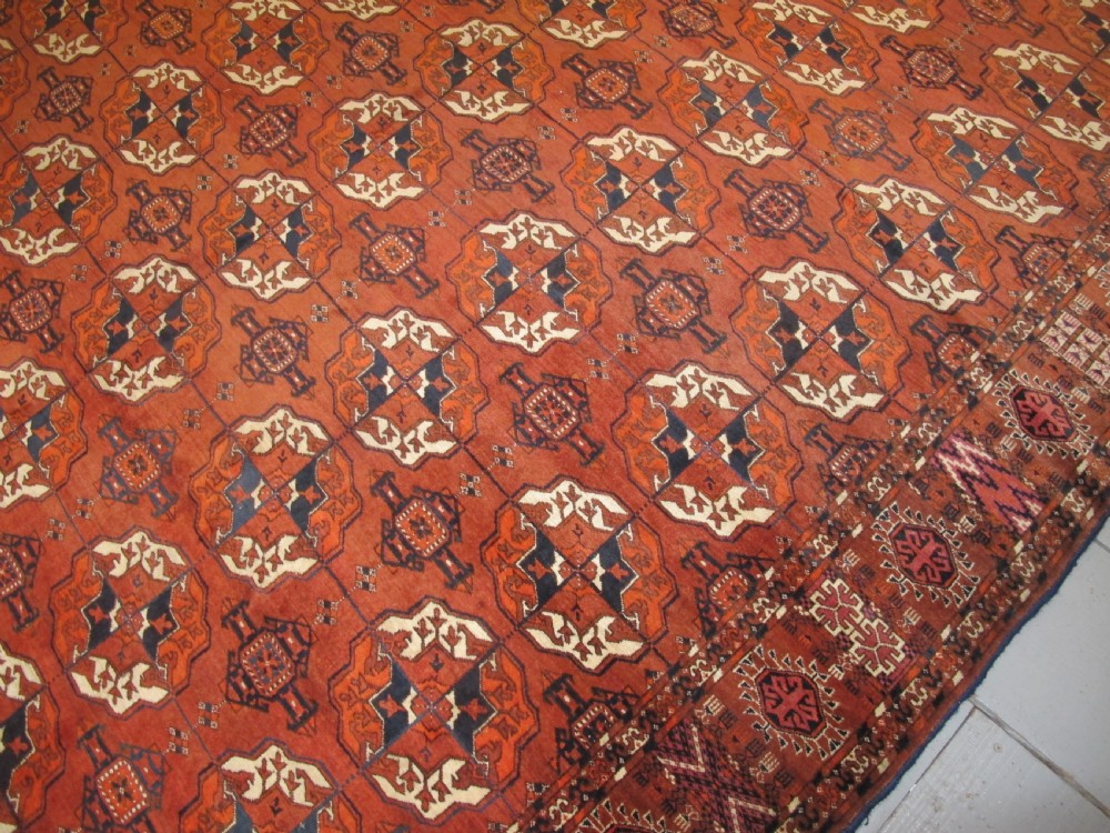 An antique hand-knotted Central Asian wool carpet featuring repeating rows of octagonal gol motifs on a terracotta red ground with detailed borders. View VII