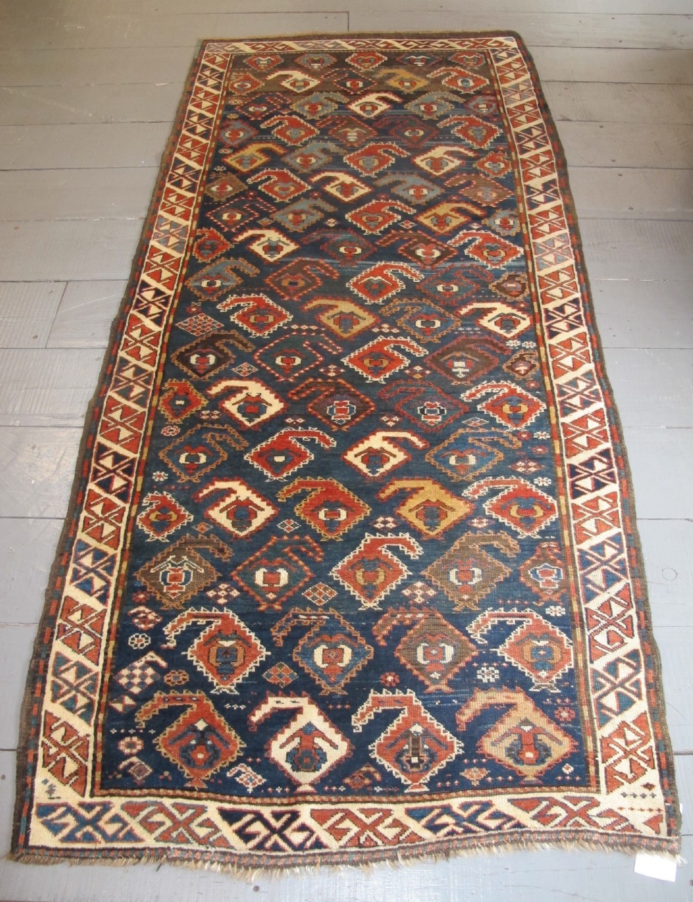 An antique late 19th-century North-West Persian hand-knotted wool runner rug featuring repeating geometric hook motifs on a dark blue field framed by geometric borders.