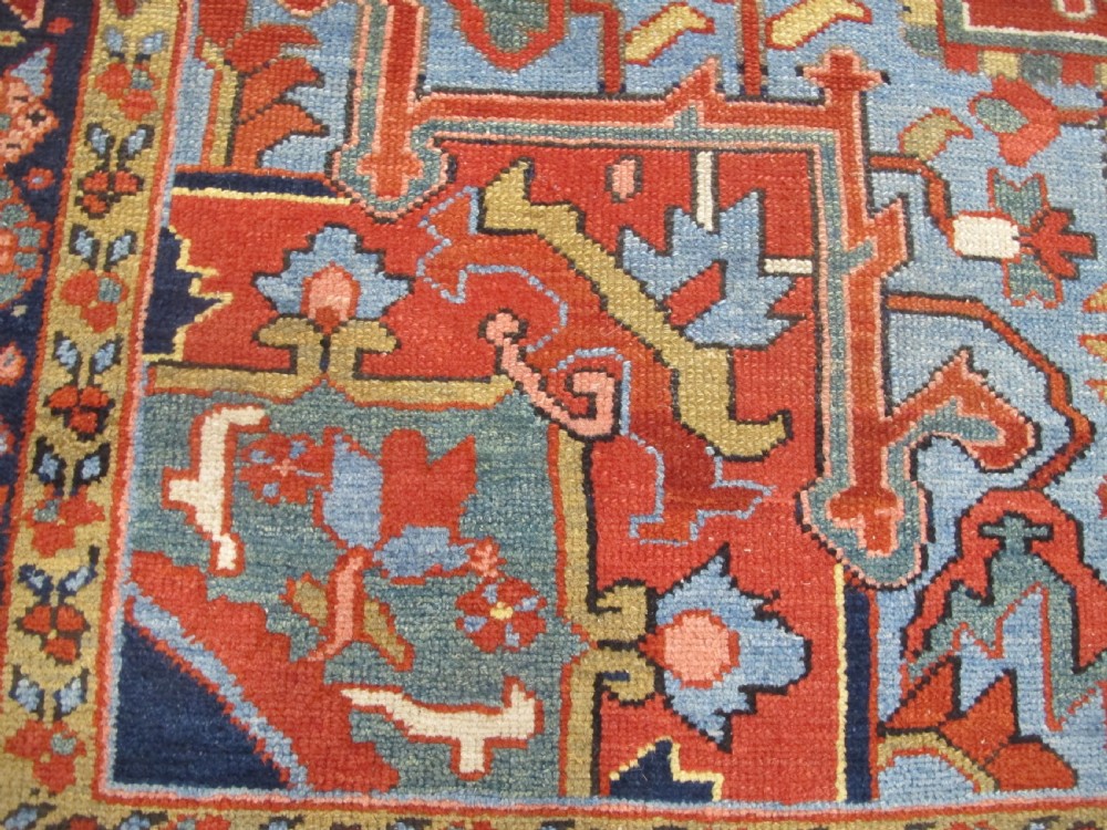 An antique Persian Karaja wool carpet featuring a large central geometric medallion surrounded by intricate red, blue, and light blue geometric borders. View V