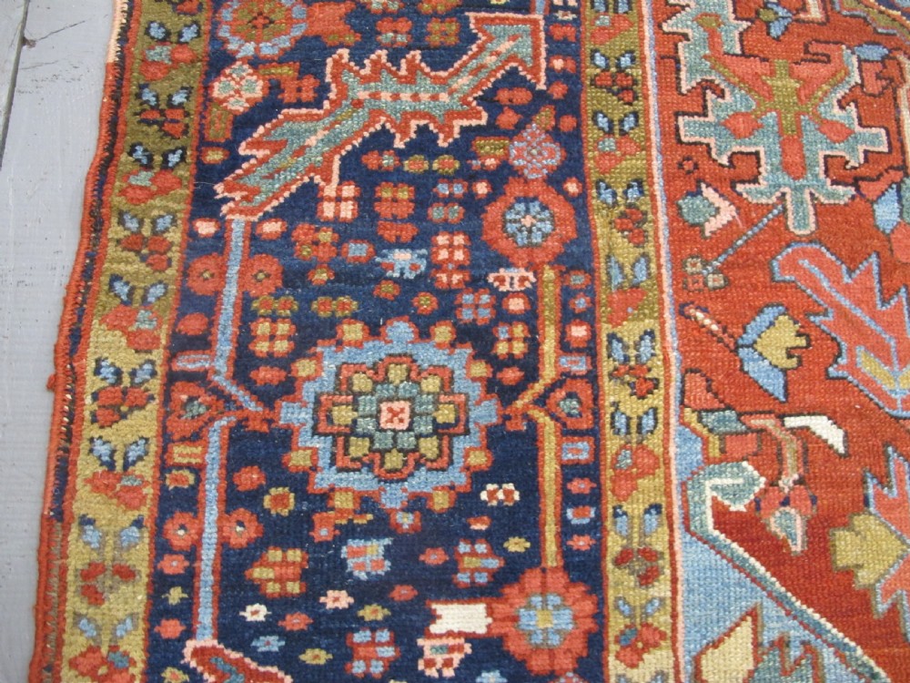 An antique Persian Karaja wool carpet featuring a large central geometric medallion surrounded by intricate red, blue, and light blue geometric borders. View VIII