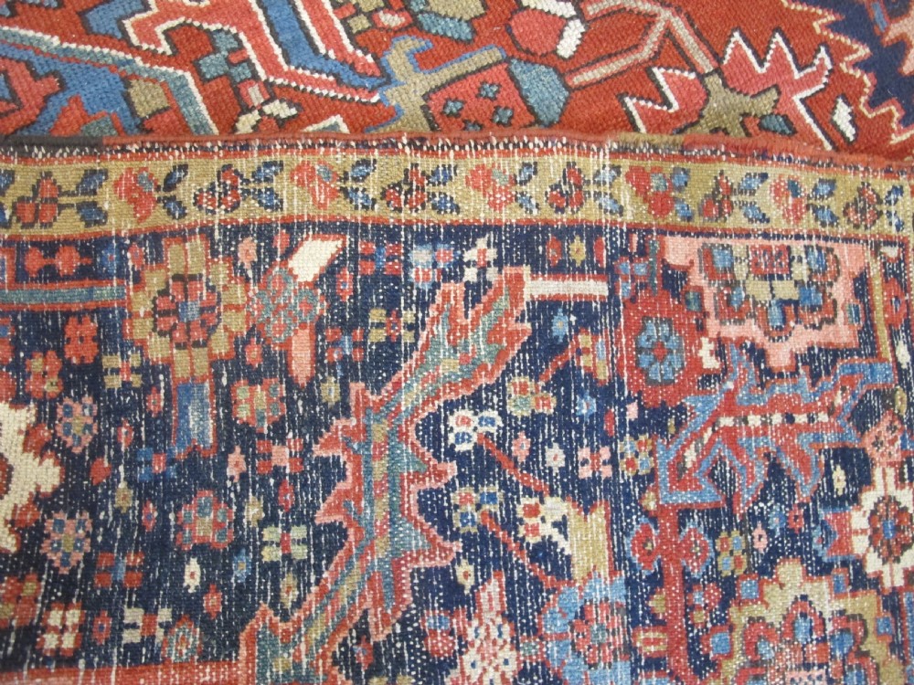 An antique Persian Karaja wool carpet featuring a large central geometric medallion surrounded by intricate red, blue, and light blue geometric borders. View XI
