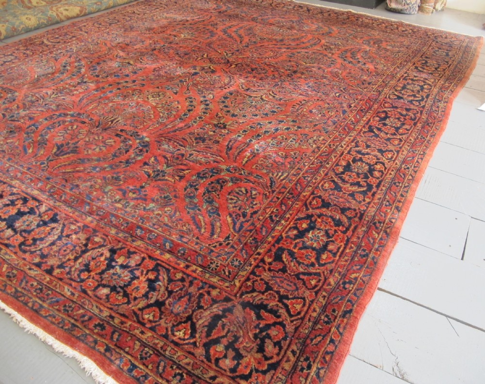 A large hand-knotted Persian Sarouk carpet featuring a dense floral pattern on a rose red field with a navy blue border. View III