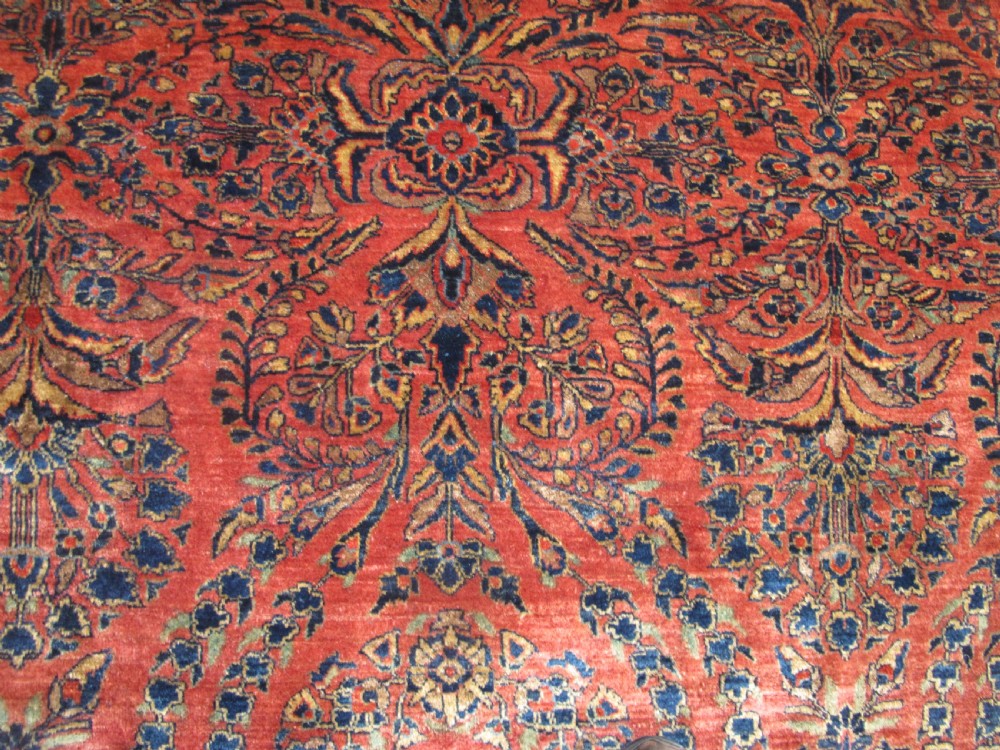 A large hand-knotted Persian Sarouk carpet featuring a dense floral pattern on a rose red field with a navy blue border. View XI