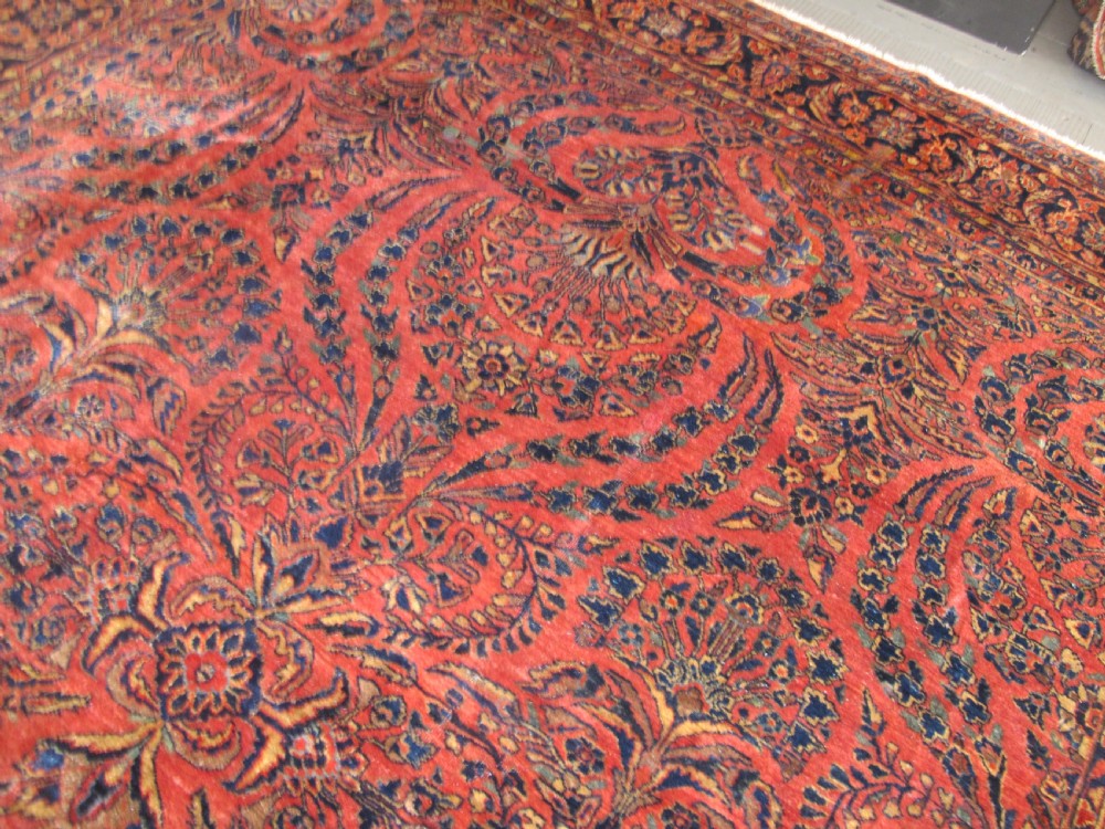 A large hand-knotted Persian Sarouk carpet featuring a dense floral pattern on a rose red field with a navy blue border. View XIII
