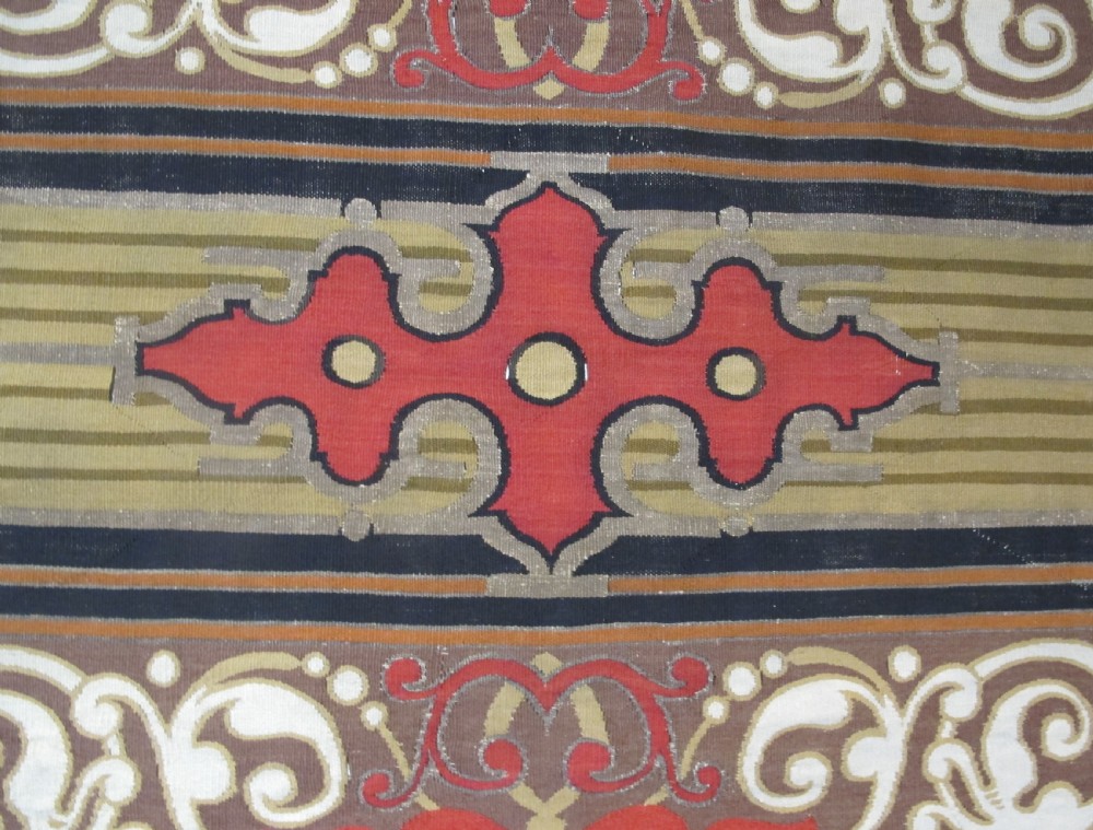 A long horizontal European wool tapestry panel featuring ornate scrolling foliage, geometric motifs, and metallic thread detailing in tones of red, olive, and beige. View VIII