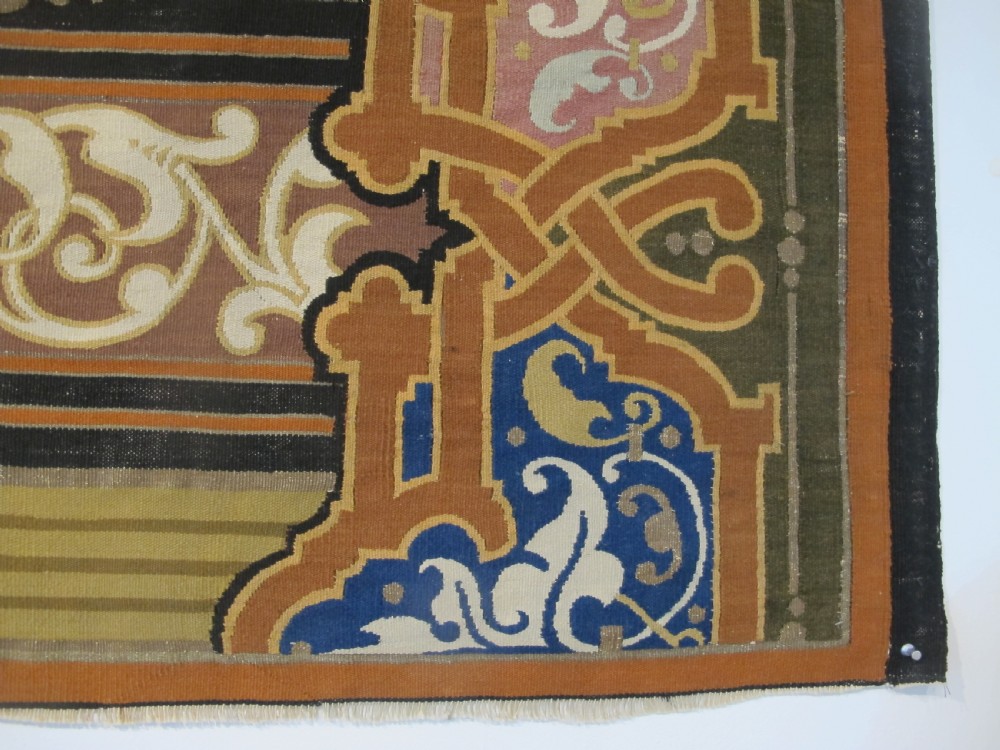 A long horizontal European wool tapestry panel featuring ornate scrolling foliage, geometric motifs, and metallic thread detailing in tones of red, olive, and beige. View IX