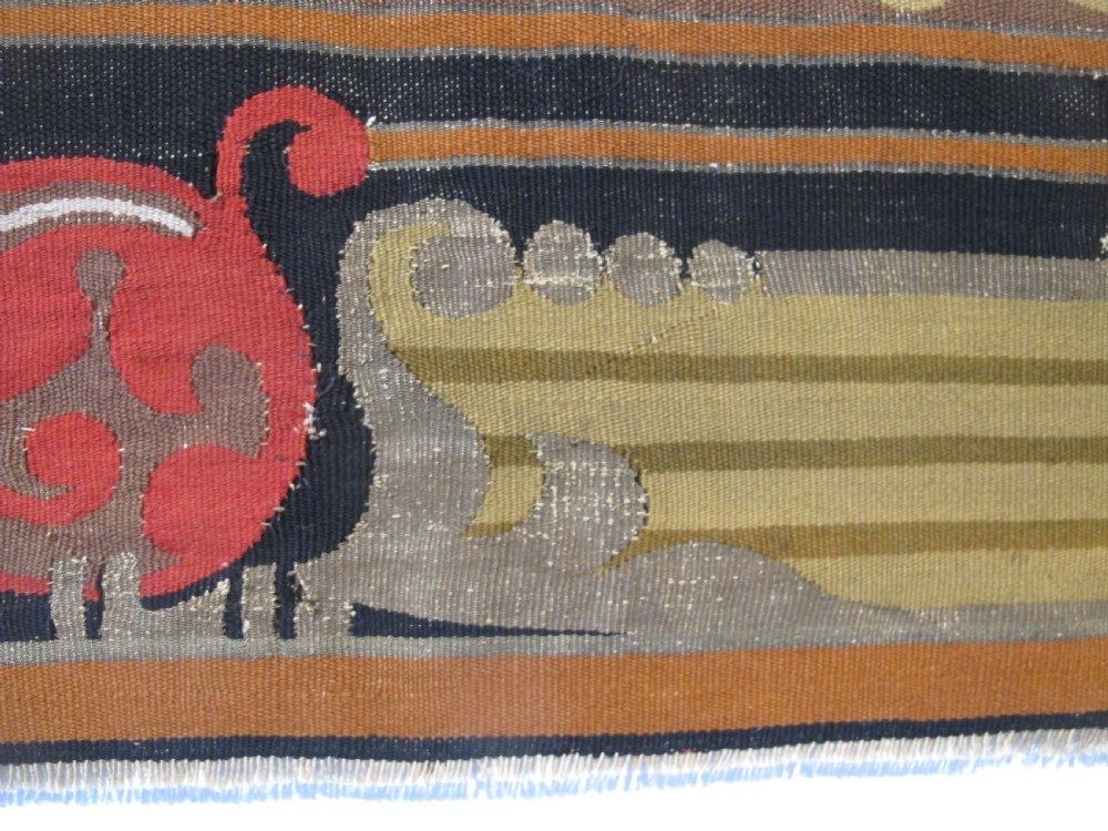 A long horizontal European wool tapestry panel featuring ornate scrolling foliage, geometric motifs, and metallic thread detailing in tones of red, olive, and beige. View XIII