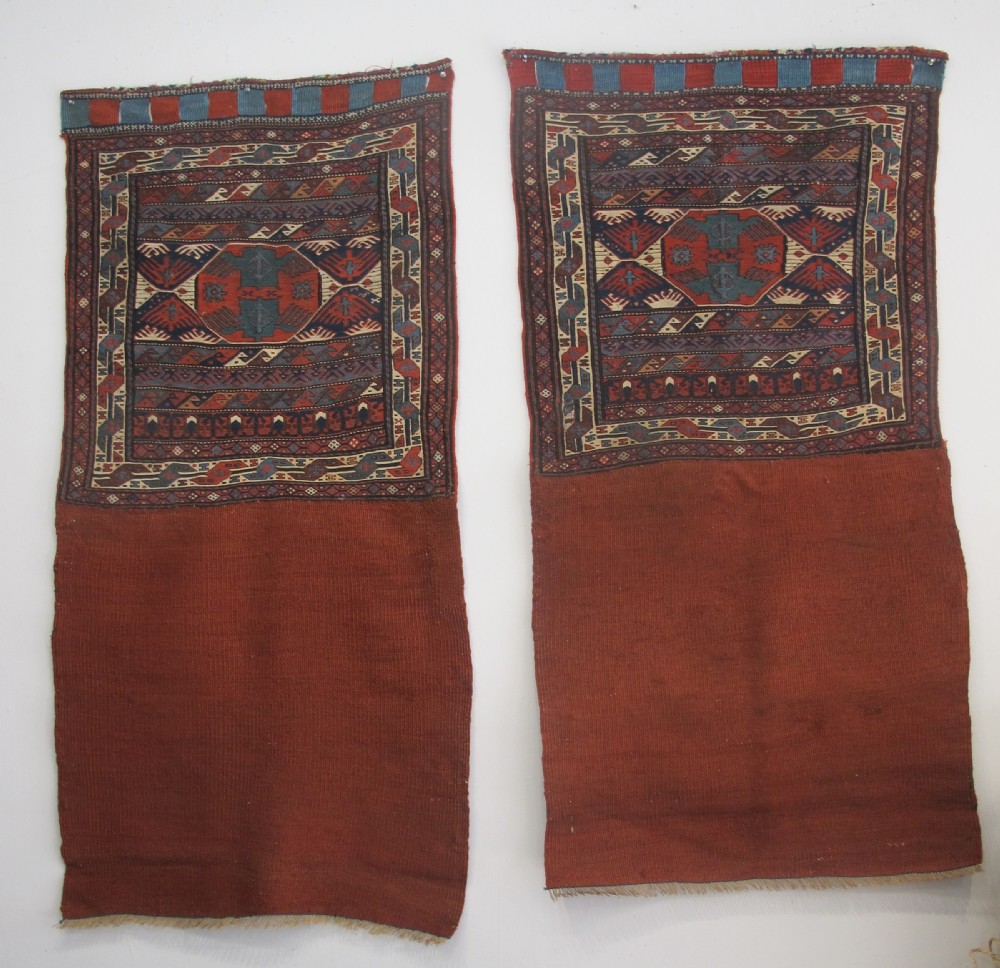 A pair of antique Caucasian Shahsavan soumac woven bags featuring geometric medallions in terracotta red, navy blue, and cream wool with decorative loops along the top edge. View II