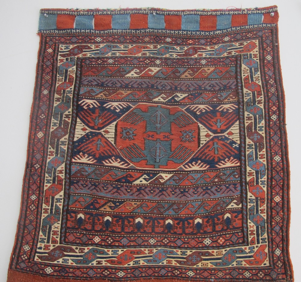 A pair of antique Caucasian Shahsavan soumac woven bags featuring geometric medallions in terracotta red, navy blue, and cream wool with decorative loops along the top edge. View III