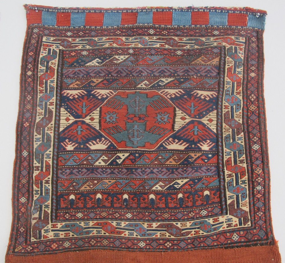 A pair of antique Caucasian Shahsavan soumac woven bags featuring geometric medallions in terracotta red, navy blue, and cream wool with decorative loops along the top edge. View IV