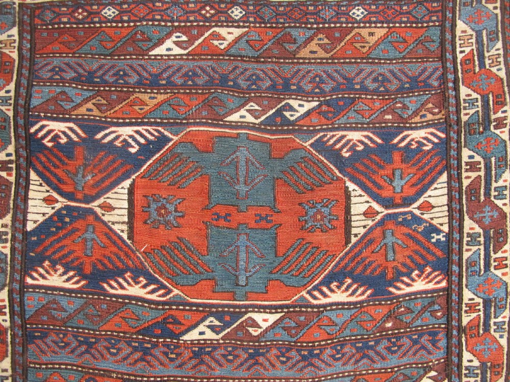 A pair of antique Caucasian Shahsavan soumac woven bags featuring geometric medallions in terracotta red, navy blue, and cream wool with decorative loops along the top edge. View V