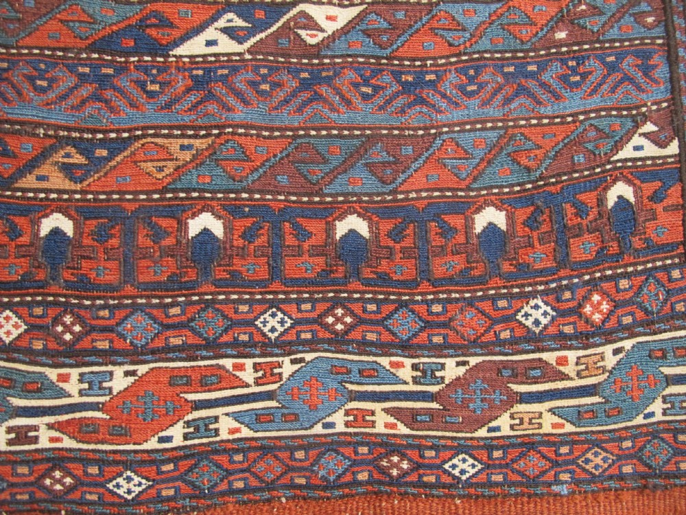 A pair of antique Caucasian Shahsavan soumac woven bags featuring geometric medallions in terracotta red, navy blue, and cream wool with decorative loops along the top edge. View VI