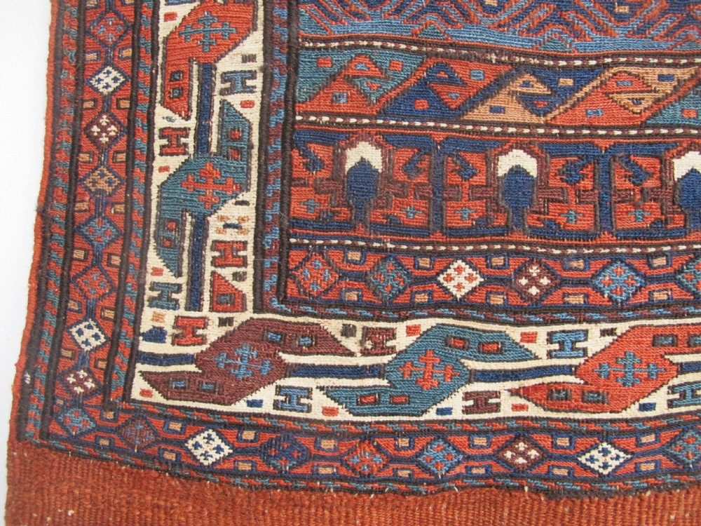 A pair of antique Caucasian Shahsavan soumac woven bags featuring geometric medallions in terracotta red, navy blue, and cream wool with decorative loops along the top edge. View VII
