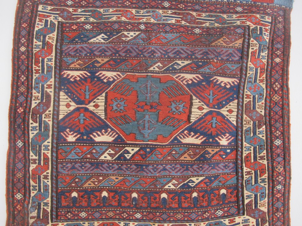 A pair of antique Caucasian Shahsavan soumac woven bags featuring geometric medallions in terracotta red, navy blue, and cream wool with decorative loops along the top edge. View VIII