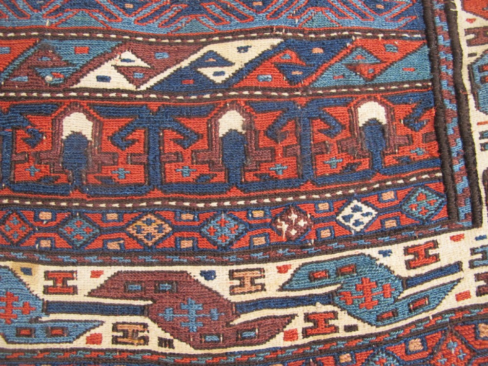 A pair of antique Caucasian Shahsavan soumac woven bags featuring geometric medallions in terracotta red, navy blue, and cream wool with decorative loops along the top edge. View IX