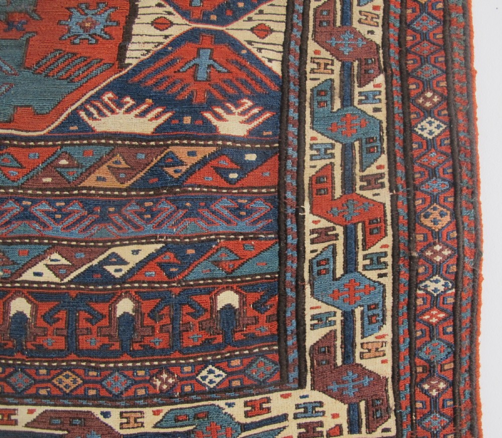 A pair of antique Caucasian Shahsavan soumac woven bags featuring geometric medallions in terracotta red, navy blue, and cream wool with decorative loops along the top edge. View X