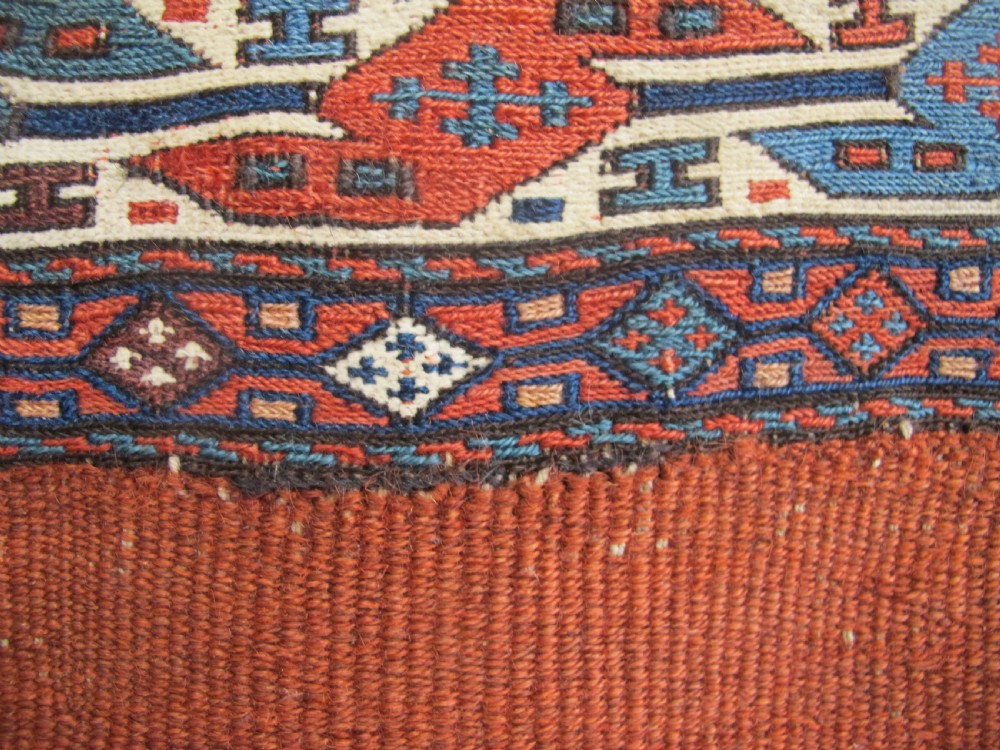A pair of antique Caucasian Shahsavan soumac woven bags featuring geometric medallions in terracotta red, navy blue, and cream wool with decorative loops along the top edge. View XII
