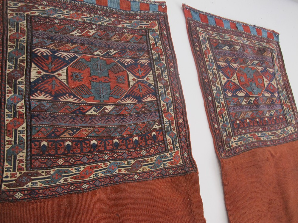 A pair of antique Caucasian Shahsavan soumac woven bags featuring geometric medallions in terracotta red, navy blue, and cream wool with decorative loops along the top edge. View XIII