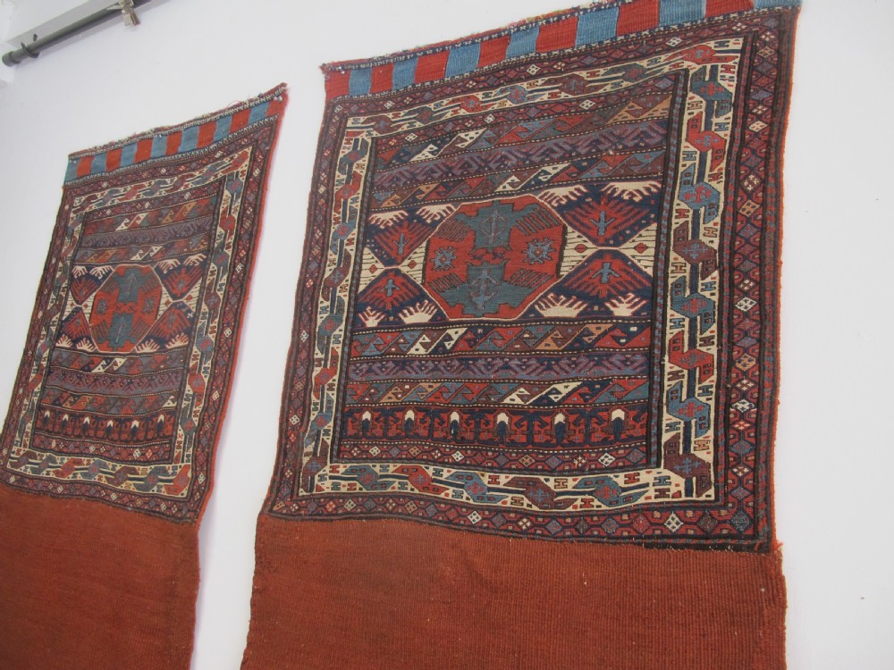 A pair of antique Caucasian Shahsavan soumac woven bags featuring geometric medallions in terracotta red, navy blue, and cream wool with decorative loops along the top edge. View XIV