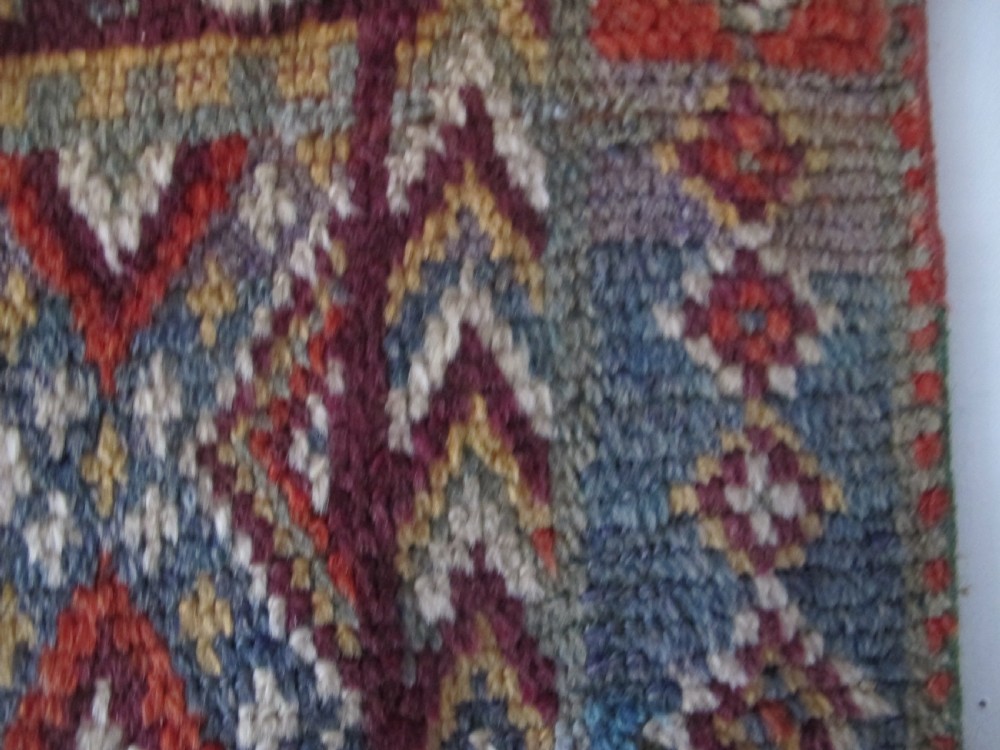 An antique rectangular Moroccan Glaoui rug featuring geometric diamond and chevron patterns in terracotta red, ochre, cream, and charcoal tones. View III