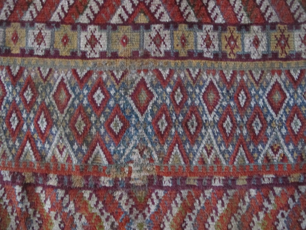 An antique rectangular Moroccan Glaoui rug featuring geometric diamond and chevron patterns in terracotta red, ochre, cream, and charcoal tones. View VIII