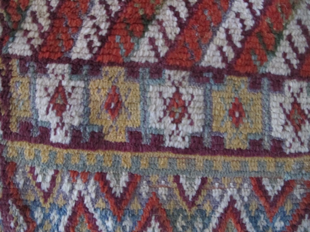 An antique rectangular Moroccan Glaoui rug featuring geometric diamond and chevron patterns in terracotta red, ochre, cream, and charcoal tones. View IX