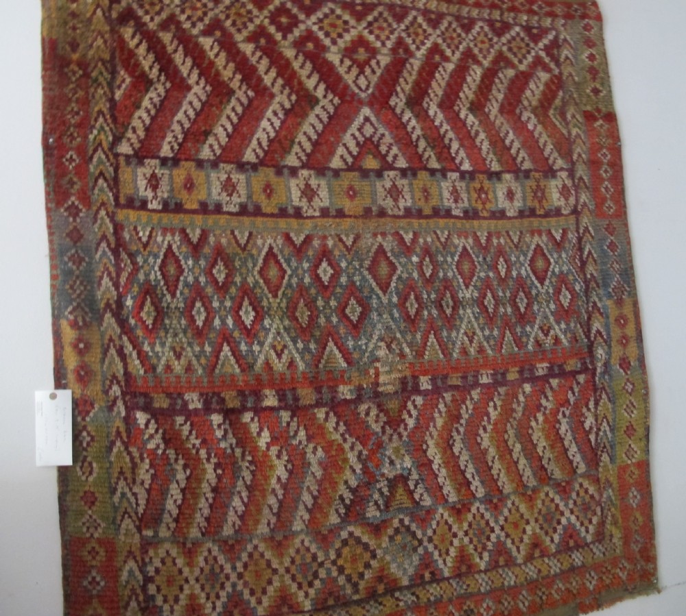 An antique rectangular Moroccan Glaoui rug featuring geometric diamond and chevron patterns in terracotta red, ochre, cream, and charcoal tones. View X
