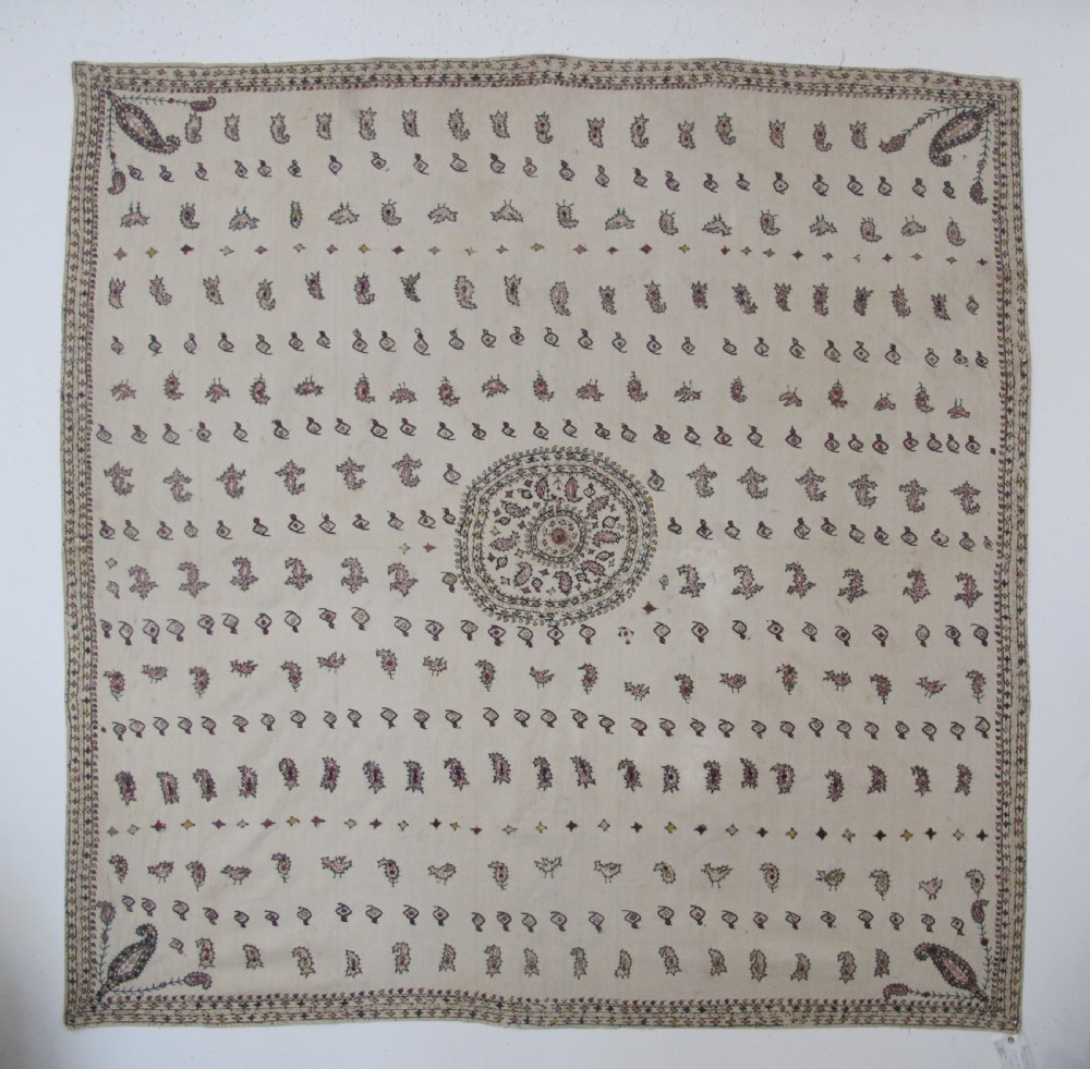 A square cream silk embroidered textile with a central circular medallion surrounded by repeating rows of small boteh motifs and a patterned border.