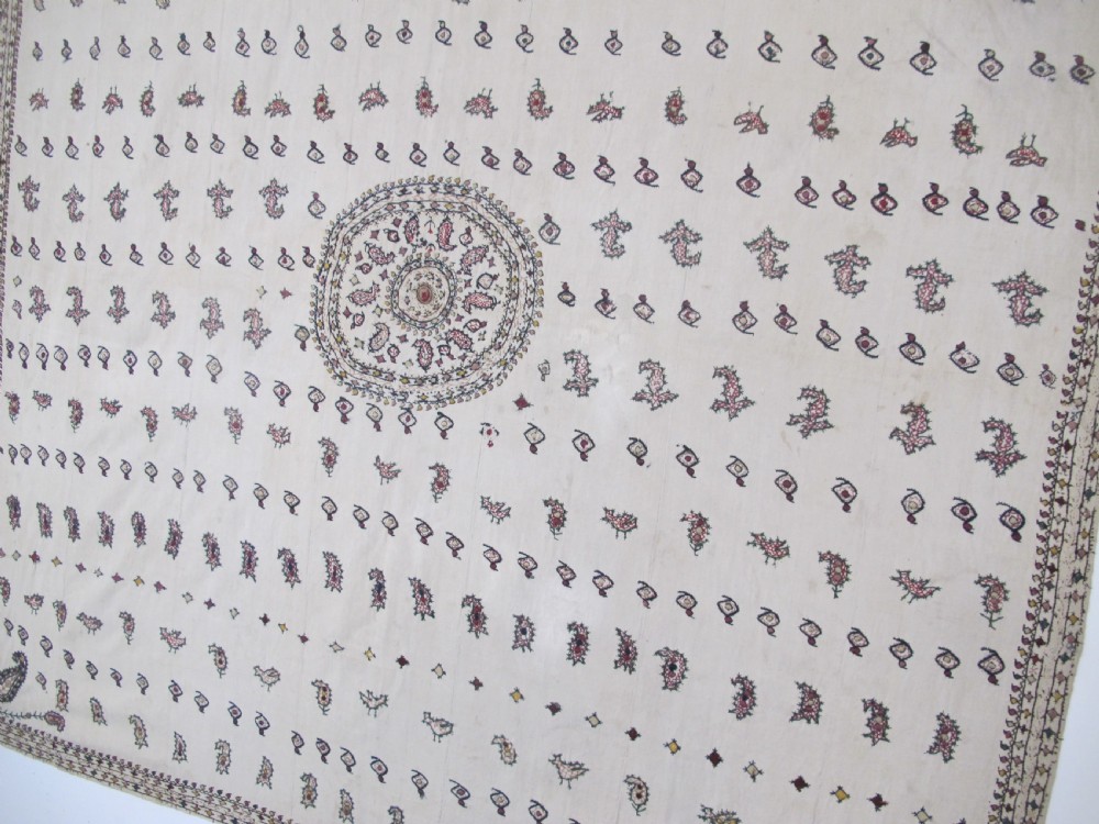 A square cream silk embroidered textile with a central circular medallion surrounded by repeating rows of small boteh motifs and a patterned border. View IX