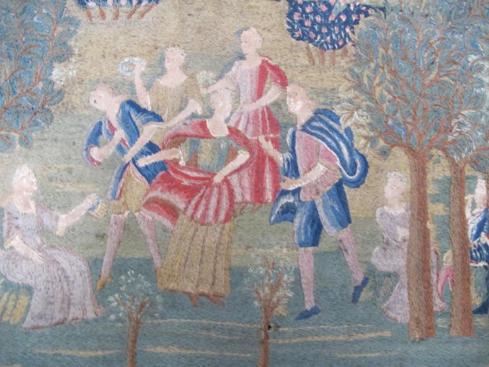 An antique square silk needlework panel displaying figurative pastoral scenes inside a wide floral border. View III