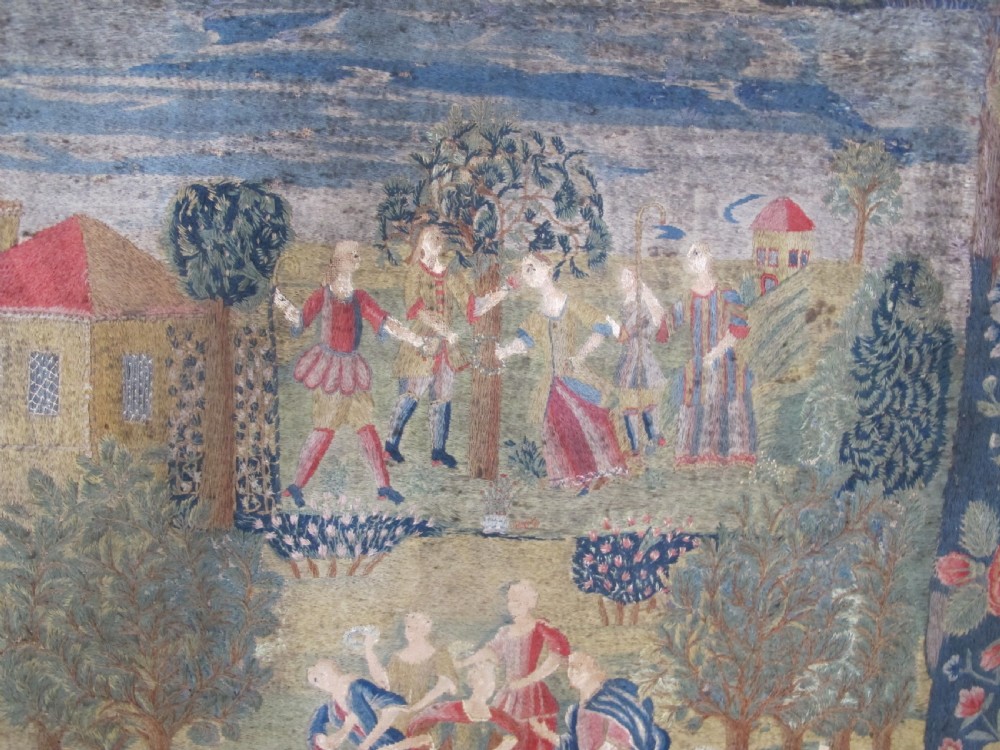 An antique square silk needlework panel displaying figurative pastoral scenes inside a wide floral border. View V