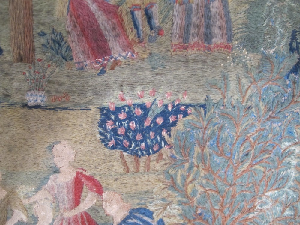 An antique square silk needlework panel displaying figurative pastoral scenes inside a wide floral border. View VI