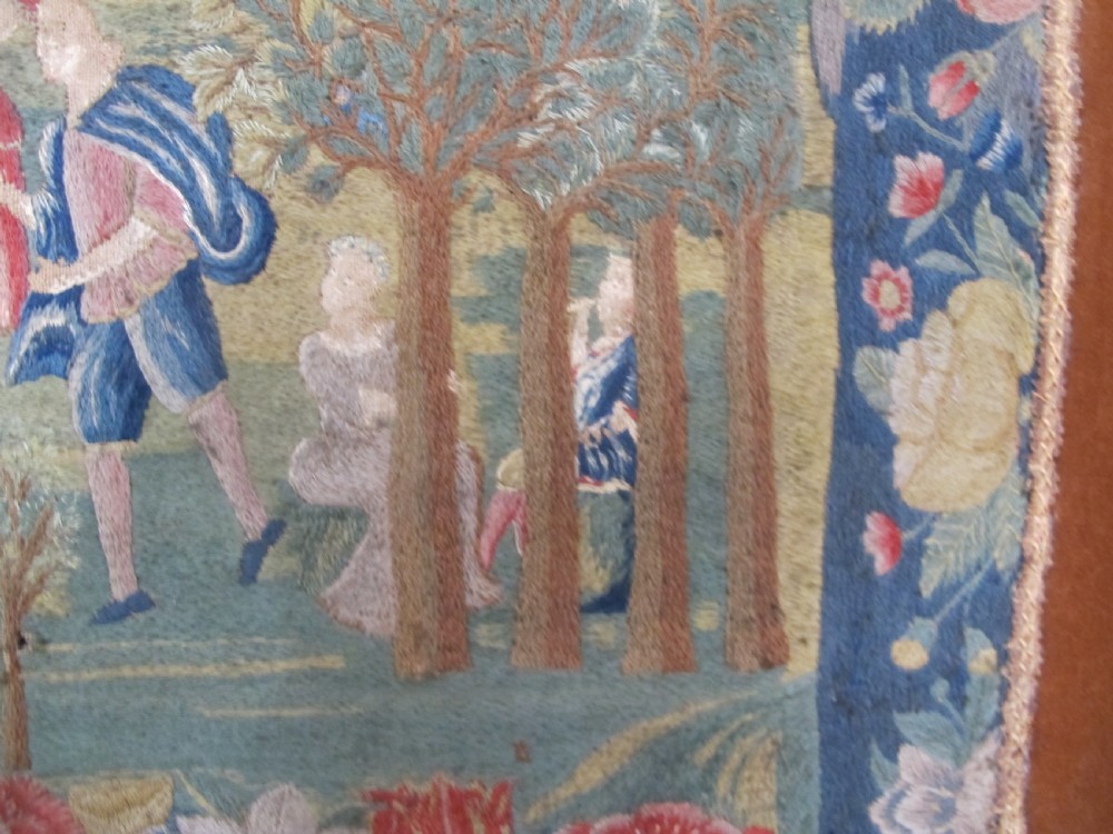 An antique square silk needlework panel displaying figurative pastoral scenes inside a wide floral border. View X