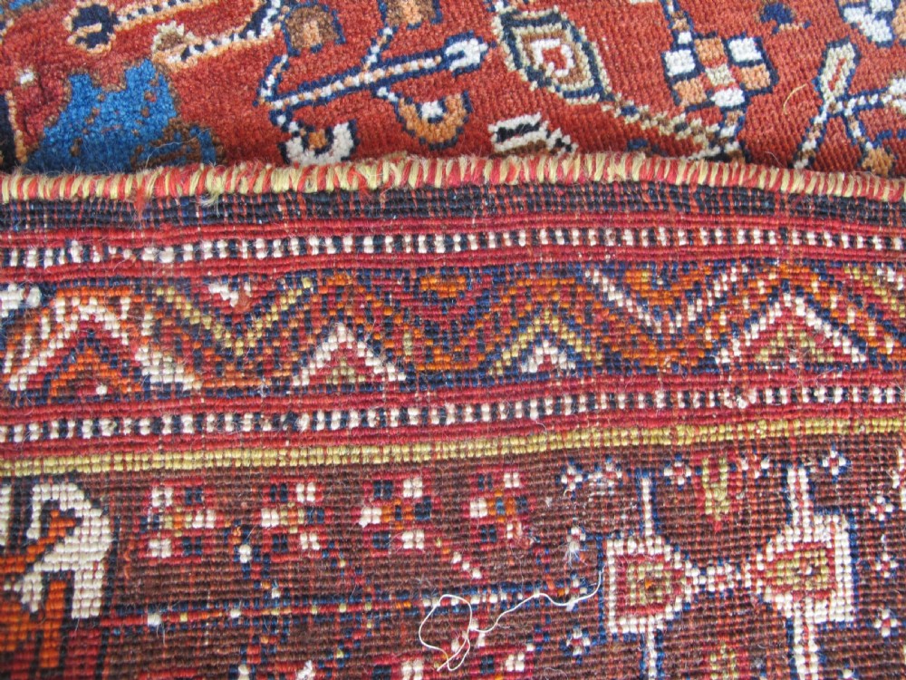 An antique Qashqai wool rug featuring a central diamond medallion, geometric tribal motifs, and intricate borders in shades of terracotta red, navy indigo, and cream. View XIII
