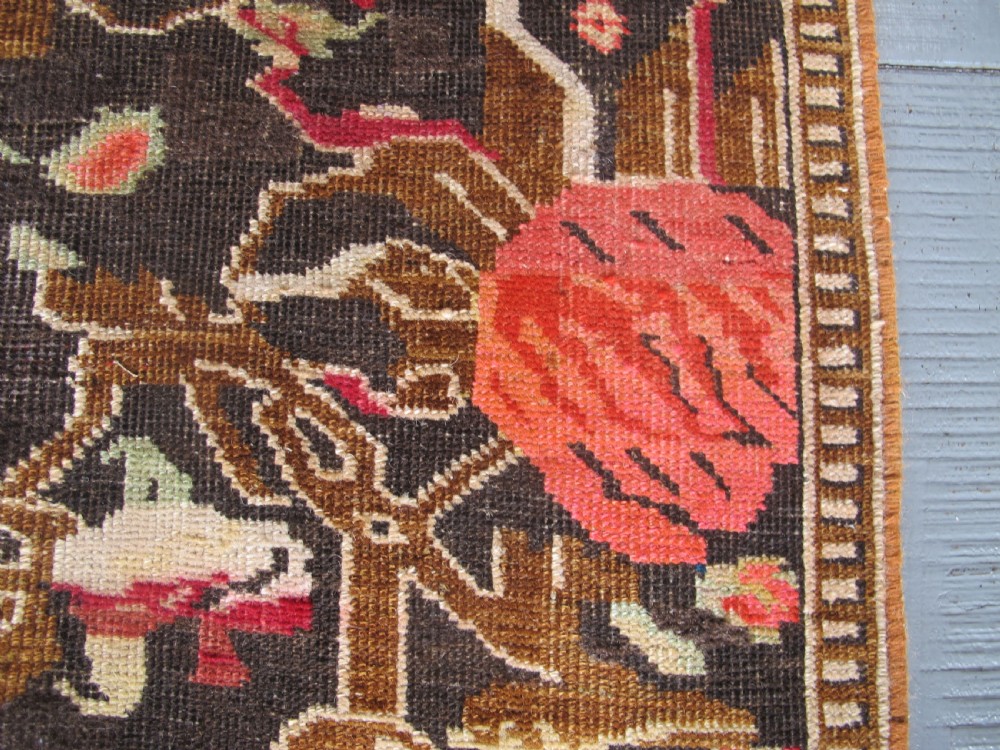 A long antique hand-knotted wool runner featuring red floral motifs and scrolling foliage against a dark brown background. View III