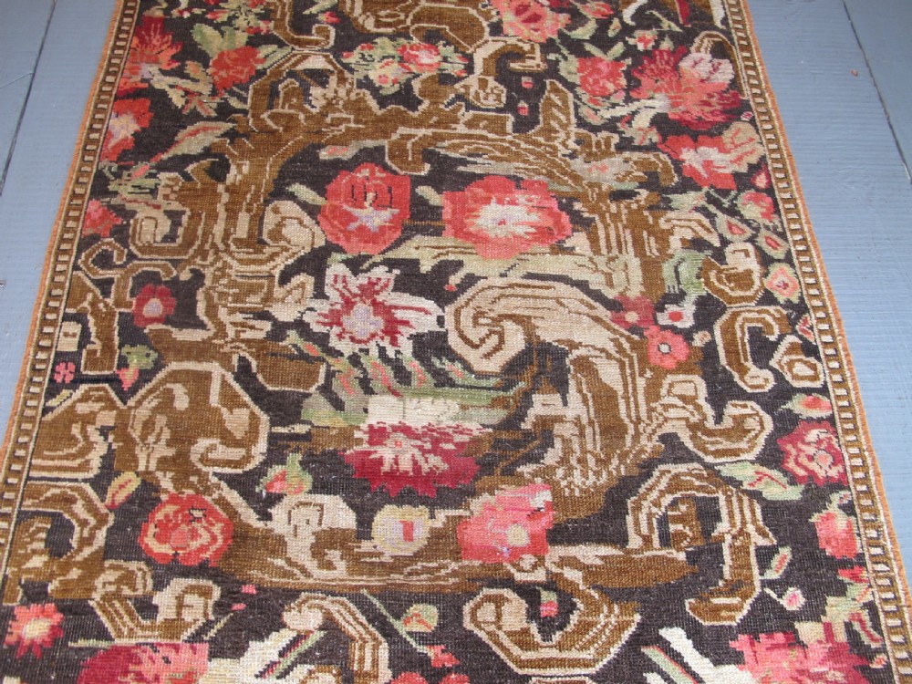 A long antique hand-knotted wool runner featuring red floral motifs and scrolling foliage against a dark brown background. View IV