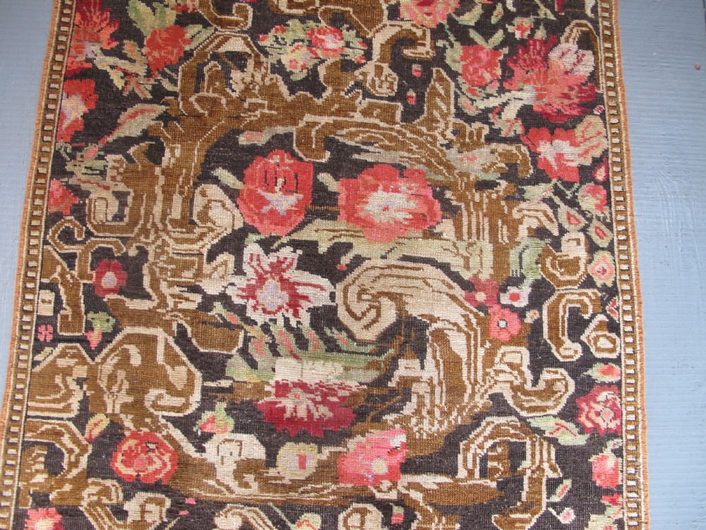A long antique hand-knotted wool runner featuring red floral motifs and scrolling foliage against a dark brown background. View V
