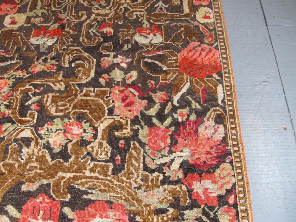 A long antique hand-knotted wool runner featuring red floral motifs and scrolling foliage against a dark brown background. View VI