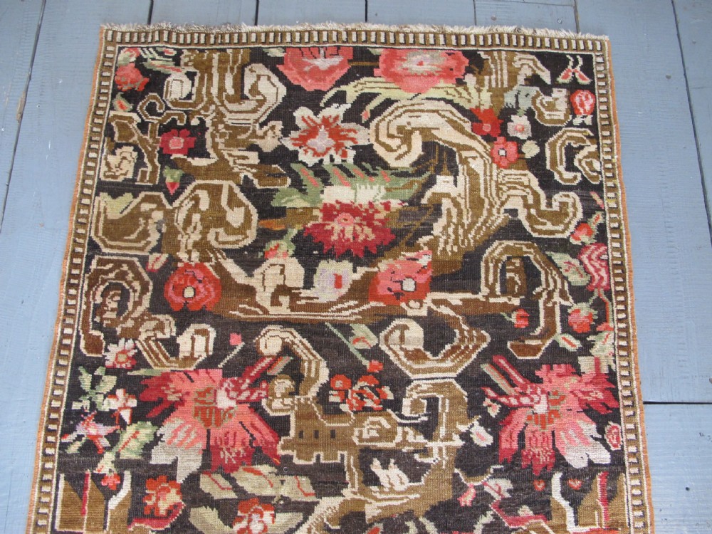 A long antique hand-knotted wool runner featuring red floral motifs and scrolling foliage against a dark brown background. View VII