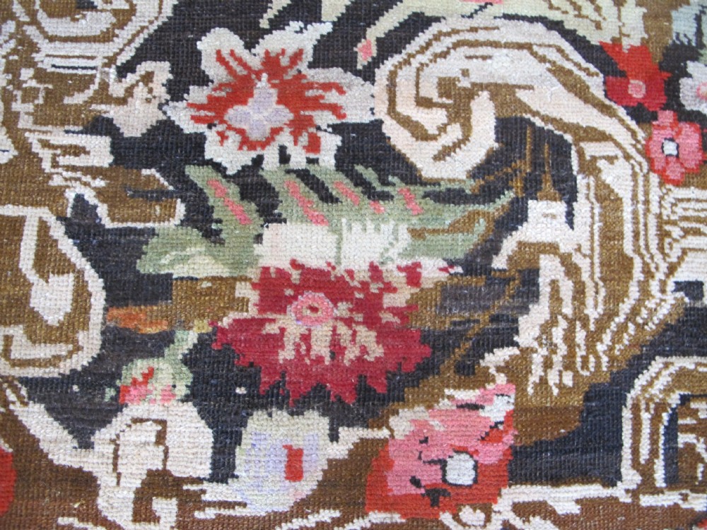 A long antique hand-knotted wool runner featuring red floral motifs and scrolling foliage against a dark brown background. View VIII